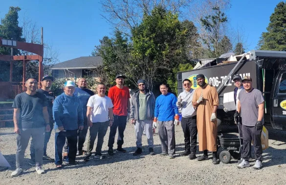 A group of people standing in front of a garbage truck